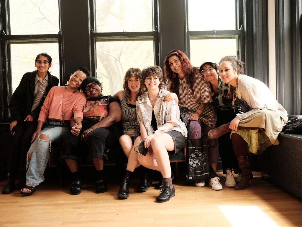 Image: A group photo of some members of the Sixty team at Haymarket House for the 2025 Midwest Arts Writers Convening. Left to right: Mrritika Ghosh, Tempestt Hazel, Ireashia M. Bennett, Christina Nafziger, Livy Snyder, Luz Magdaleno-Flores, Katia Fuentes Perez, Nadia John. Image made by Seed Lynn.