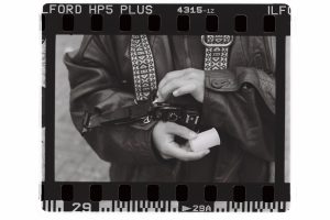 A black and white film scan captures photographer Han on cam holding their camera. Photo by Genesis Falls.